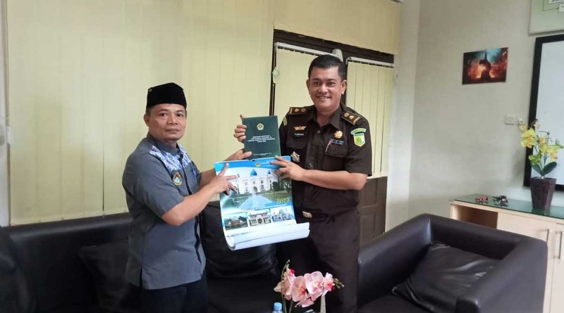 Sekretaris DPD LDII Kukar Aris Teguh Rahayu menyerahkan Buku Munas IX DPP LDII dan Kalender 2023 kepada Kasi Intel Kejari Fariz Oktan. Foto: Istimewa