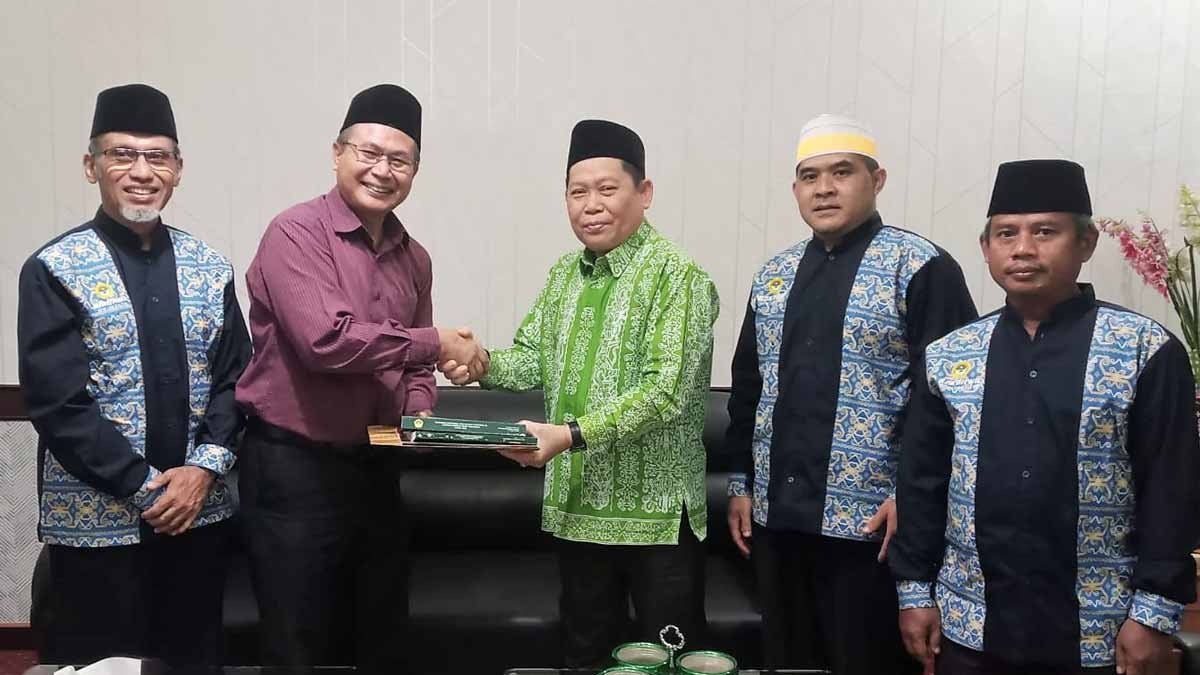 Ketua DPW LDII Provinsi Kaltim Prof. Candra menyerahkan Buku Hasil Munas IX LDII kepada Kakanwil Kemenag Kaltim Drs. H. Abdul Khalik, M.Pd di ruang kerjanya, Tampak juga jajaran pengurus harian DPW LDII Kaltim, Kamis (16/3). Foto: LINES